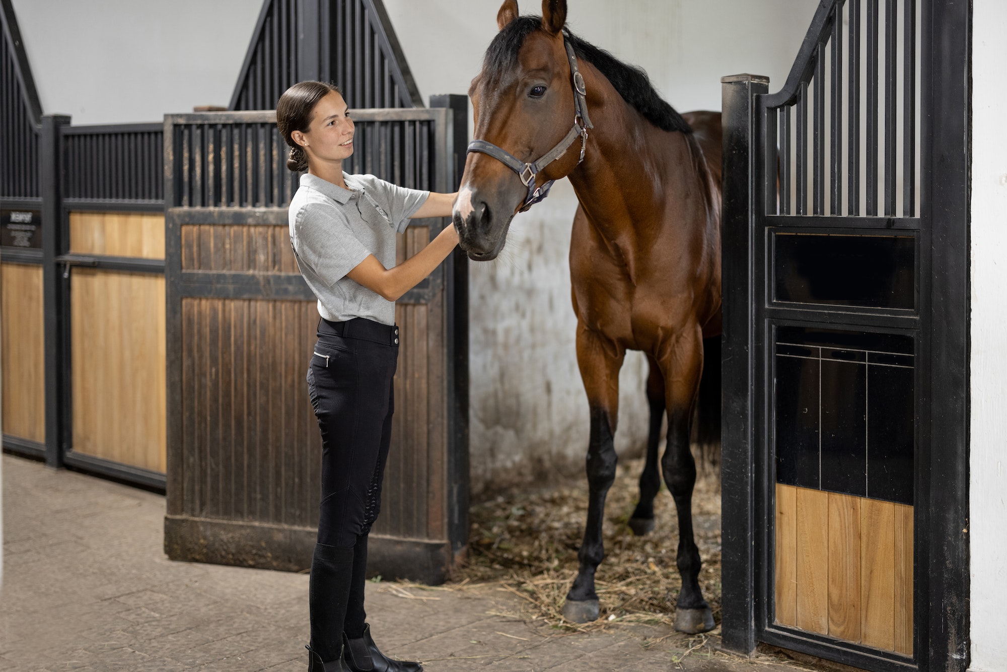 Female horseman feeding her horse in stable